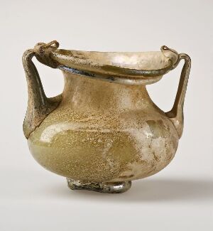  An ancient beige ceramic pot with two outward-curving handles and a weathered surface showing a gradient from dark brown at the bottom to a light cream color at the top.