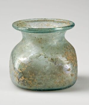  A translucent pale aqua antique glass vessel with a bulbous body and flared neck, displaying a weathered surface with patches of brown and ochre.