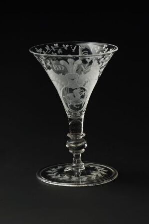  An elegantly crafted transparent glass goblet with an intricate stem and decorative etching on the bowl, set against a solid black background to accentuate its details. Artist name and title are unknown.