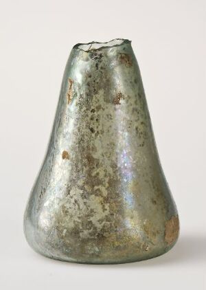  An antique metal conical object with a broad round base and a narrow opening, featuring a weathered surface with silver-gray, green, and brown tones, suggestive of tarnish and corrosion, possibly a vase or decorative piece.