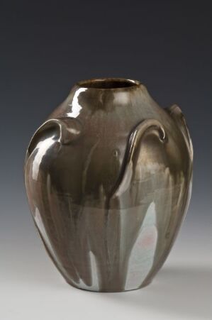  A glossy ceramic vase with fluid, curving handles and a gradient of brown hues accented by darker glaze lines, set against a neutral gray background.