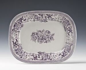  Oblong white flintware serving platter with intricate blue floral and foliate press-decorations around the rim and at the center, set against a neutral background. Artist name and title are unknown.