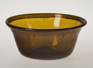  A smoky brown translucent bowl with an amber rim, sitting on a neutral light grey background.