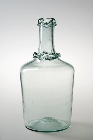  An antique, rectangular greenish glass bottle with a rounded edge and an irregular, decorative ring around its neck stands against a soft white and light gray gradient background.