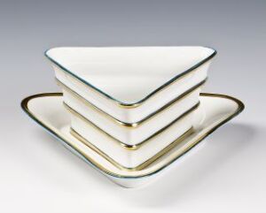  A stack of four square white porcelain dishes with gold trim, designed by Nora Gulbrandsen, on a light grey gradient background.