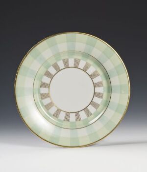  Plate designed by Porsgrunds Porselænsfabrik AS, crafted from feldspar porcelain with an overglaze checkered pattern in light green and brown, finished with a metallic gold rim. The center is a plain white circle, set against a dark background.