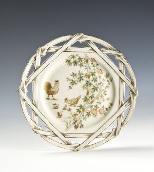  An octagonal feltspat porcelain plate by Porsgrunds Porselænsfabrik AS featuring an over-glaze decoration of a gold and brown bird in the center, with smaller birds and floral motifs in shades of green, pink, and yellow, framed by a braided green and gold edge.