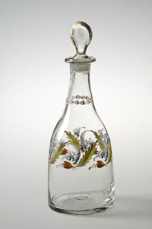  A transparent glass decanter with a slender neck and intricate green, yellow, and orange floral painting on the body, topped with a teardrop-shaped stopper, against a plain background.