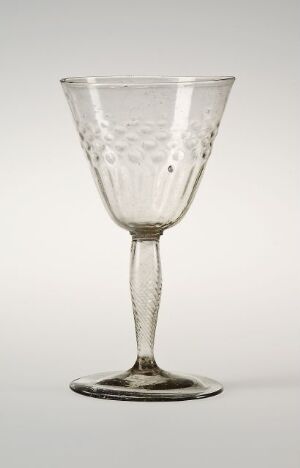  A transparent glass goblet with an etched bell-shaped bowl, slender stem, and flat base, set against a light gray background.