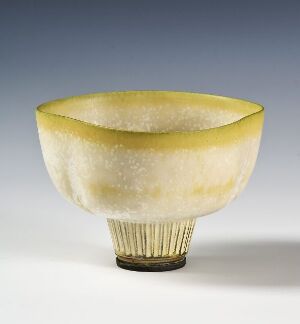  A "Farsta" stoneware bowl designed by Wilhelm Kåge, featuring a speckled pale yellow and off-white interior with a bright yellow rim, a textured lower half with vertical ridges ending in a dark base, against a plain background.