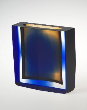  A modern abstract sculpture with a distorted rectangular loop-like shape, featuring a gradient of deep blues blending into amber at the center, suggestive of polished glass, against a white background with a soft shadow indicating freestanding placement. Artist and title unknown.