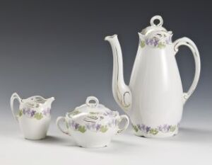  Elegant porcelain tableware set by Porsgrunds Porselænsfabrik AS consisting of a teapot, sugar bowl with lid, and creamer, predominantly white with delicate purple and green floral designs and gold accents.