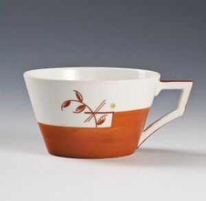  A ceramic cup by Porsgrunds Porselænsfabrik AS featuring a two-tone color scheme with a white upper and earthy brown lower half. Decorative red-brown botanical illustrations adorn the white section, and the cup has a distinctively designed triangular handle.