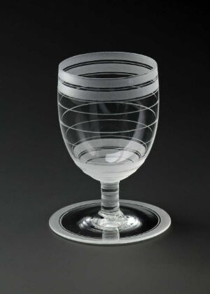  A blown glass with engraved spiral patterns designed by Sverre Pettersen, exhibiting transparent and slightly smoky glass with a rounded bowl, short stem, and a flat, flared base against a dark grey background.