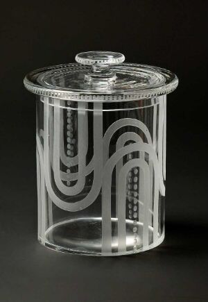  A clear glass cylindrical container with an art deco style frosted etching, featuring geometric patterns and stylized arches, placed on a dark background.