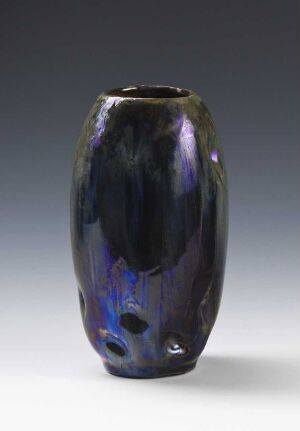  A tall, iridescent vase with a glossy black surface that reflects purples, blues, and hints of orange and green. The smooth, streamlined form sits against a soft gray gradient background.