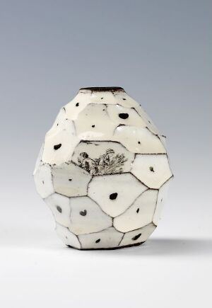  A ceramic vase by artist Anne Line Sund with a multifaceted, hexagonal design, dotted with irregular black spots on an off-white surface, against a smooth gradient gray to white background.