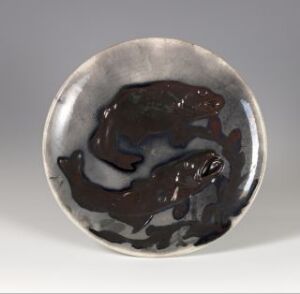  A ceramic bowl with a shallow depth featuring a mottled pattern of grays, blues, and browns with a depiction of two dark fish swimming in opposite directions, creating an artistic representation of underwater life. The artist's name and title of the piece are unknown.