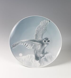  A circular artistic plate depicting a monochromatic image of an owl in mid-flight with wings spread upwards, set against a white-to-grey gradient background that evokes a serene, wintry scene.