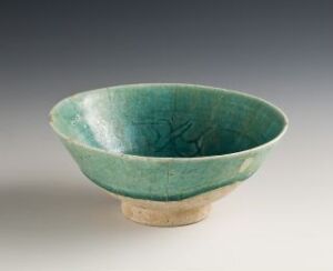  A ceramic bowl with a tapered, conical profile, featuring a vibrant teal glaze on the interior and part of the exterior, with an unglazed beige base and subtle incised decoration on the inside. No specific artist or title information provided.