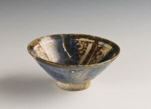  An antique ceramic bowl with sky blue to beige gradient on the outside and intricate navy and cream geometric patterns inside, displayed against a light grey background. Artist name and title are unknown.