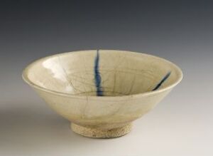  A handcrafted off-white ceramic bowl with a fine crackle glaze and two vertical cobalt blue lines painted inside, resting on a small base against a neutral background.