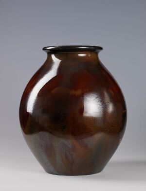  A round-bodied vase with a glossy finish, featuring swirling patterns of dark chocolate brown and caramel hues against a neutral gray background. Artist name and title are unknown.