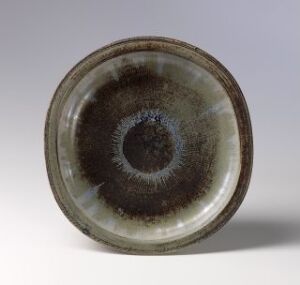  A 'Farsta' ceramic plate from Gustavsberg fabriker, featuring a gradation of brown to almost black concentric circles on a greige background with a glossy finish.