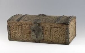  An antique wooden chest with elaborate carvings and metal hardware, including a central lockplate, set against a neutral gradient background. The chest's color is a muted brown with an aged patina, and the design features geometric and floral motifs.