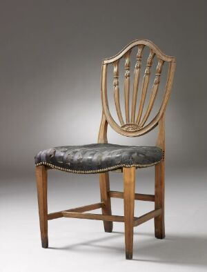 
 A vintage wooden chair with a cushioned seat upholstered in faded blue fabric, featuring an oval-shaped backrest with multiple vertical slats, set against a grey background. Artist and title unknown.