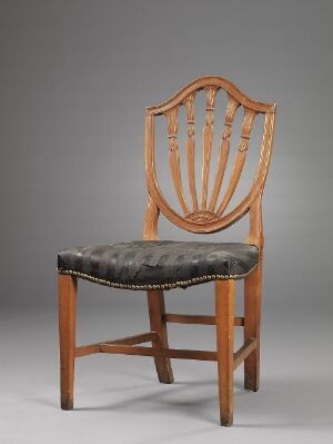  A traditional wooden chair with a curved top rail, nine spindles on the backrest, and dark tufted upholstery on the seat, against a neutral gray background.