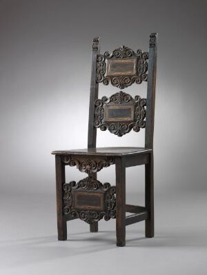  An antique ornately carved dark brown wooden chair with a high backrest featuring three decorative panels, set against a neutral gray background.