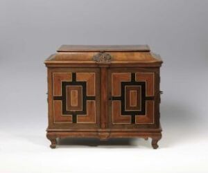  An antique wooden chest with a geometric inlay design on two doors, featuring reddish-brown tones and situated against a neutral backdrop.