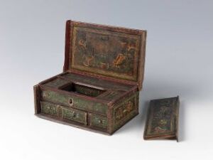  An antique burgundy red box with decorative floral and gilded motifs opened to display its compartmentalized interior, positioned next to a similarly designed smaller item, all on a light gray background.