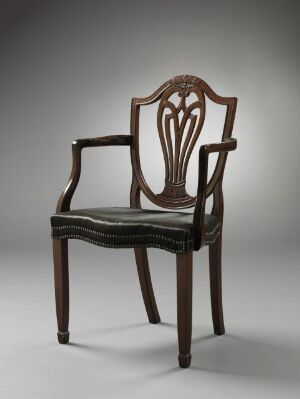  An "Armstol" mahogany armchair with carved details and a dark upholstered seat, designed by an unidentified artist. The chair features ornate openwork on the backrest and is accented with brass tacks.