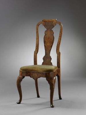  An antique-style chair with a high, ornate wooden backrest and a cushioned seat upholstered in light golden-yellow fabric, set against a soft gray background. The chair has rich, dark brown tones and gracefully curved front legs.