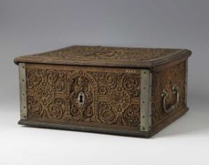  An antique, dark brown wooden chest with intricate floral and geometric carvings on all visible sides, featuring a metal lockplate in the center of the front, and metal handles on each front side, positioned against a gray background.