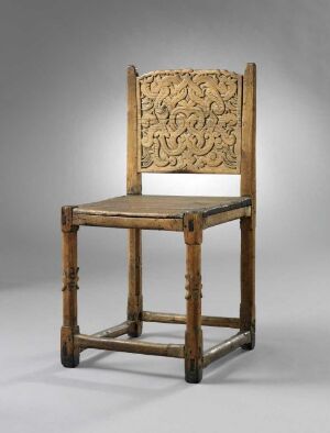  An antique wooden chair with a square, intricately carved backrest, and a woven seat, positioned against a gradient gray background. The chair exhibits a classic design with golden-brown colored wood and appears to be from a previous era.