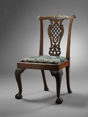  An antique chair with dark wood frame, featuring a curved crest rail with scrollwork, an openwork lattice back, cabriole front legs with claw-and-ball feet, and faded teal upholstered cushion with a subtle floral pattern.