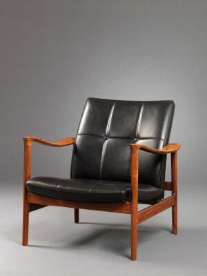  "Winston" by Torbjørn Afdal - A mid-century modern armchair with a lacquered or oil-polished palisander wood frame, featuring flat, broad armrests and angled legs. The chair is upholstered in black leather with segmented padding on the backrest, contrasting elegantly with the reddish-brown wooden frame.