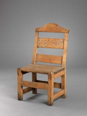  An aged, wooden chair with a rectangular backrest featuring cut-out shapes, positioned against a light grey background.