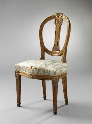  A neoclassical style chair with a lyre-carved, oval-shaped backrest, gilded detailing, and dark wooden frame. The seat is upholstered in a light fabric with a delicate floral and ribbon pattern in soft reds, greens, and golds. The chair displays polished, fluted front legs and gently curved back legs.