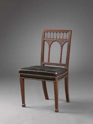  An elegant classical wooden chair with a gothic-style openwork backrest, dark polished finish, dark brown or black upholstered seat with golden piping, and decorative inlays on the tapered legs against a gray background. Artist name and title remain unknown.