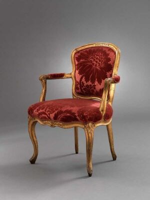  Gilded birch armchair titled "Armstol" by Johan J. Katzenberg with carved decorations and red velvet upholstery, adorned with an embossed floral motif on a neutral grey background.