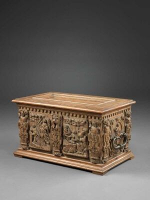  Antique wooden chest with detailed relief carvings on all visible sides, set against a neutral grey background. The chest has a flat top and is mounted on a simple base. The carvings portray intricate figures and narratives, showcasing exceptional craftsmanship. Artist name and title are unknown.