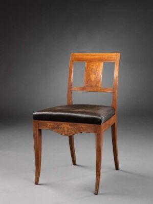  An antique wooden chair with curving legs and a dark brown leather seat, featuring an intricate lighter-colored wood inlay with a floral design on the backrest, set against a gradient gray background.