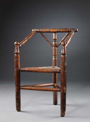  An old wooden armchair with a straight back and horizontal support bars, medium to dark brown in color, standing against a gradient grey background.