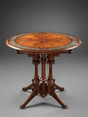  An antique round wooden table with a glossy finish and intricate carvings on the rim, supported by a central column and multiple curved legs, against a neutral gray background. Artist and title unknown.