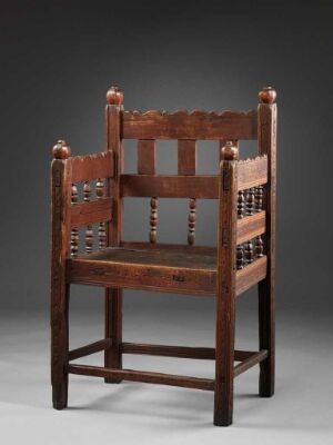  A traditional, dark brown wooden armchair with a straight horizontal backrest, three vertical back slats, turned spindle arm supports, a flat seat, and sturdy legs with horizontal stretchers, set against a neutral gray background.