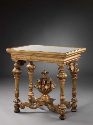  An antique, ornate rectangular table with carved, golden-finished wooden legs and a lighter-tone tabletop, set against a neutral dark gray background, highlighting the table's intricate details and craftsmanship. Artist name and title unknown.